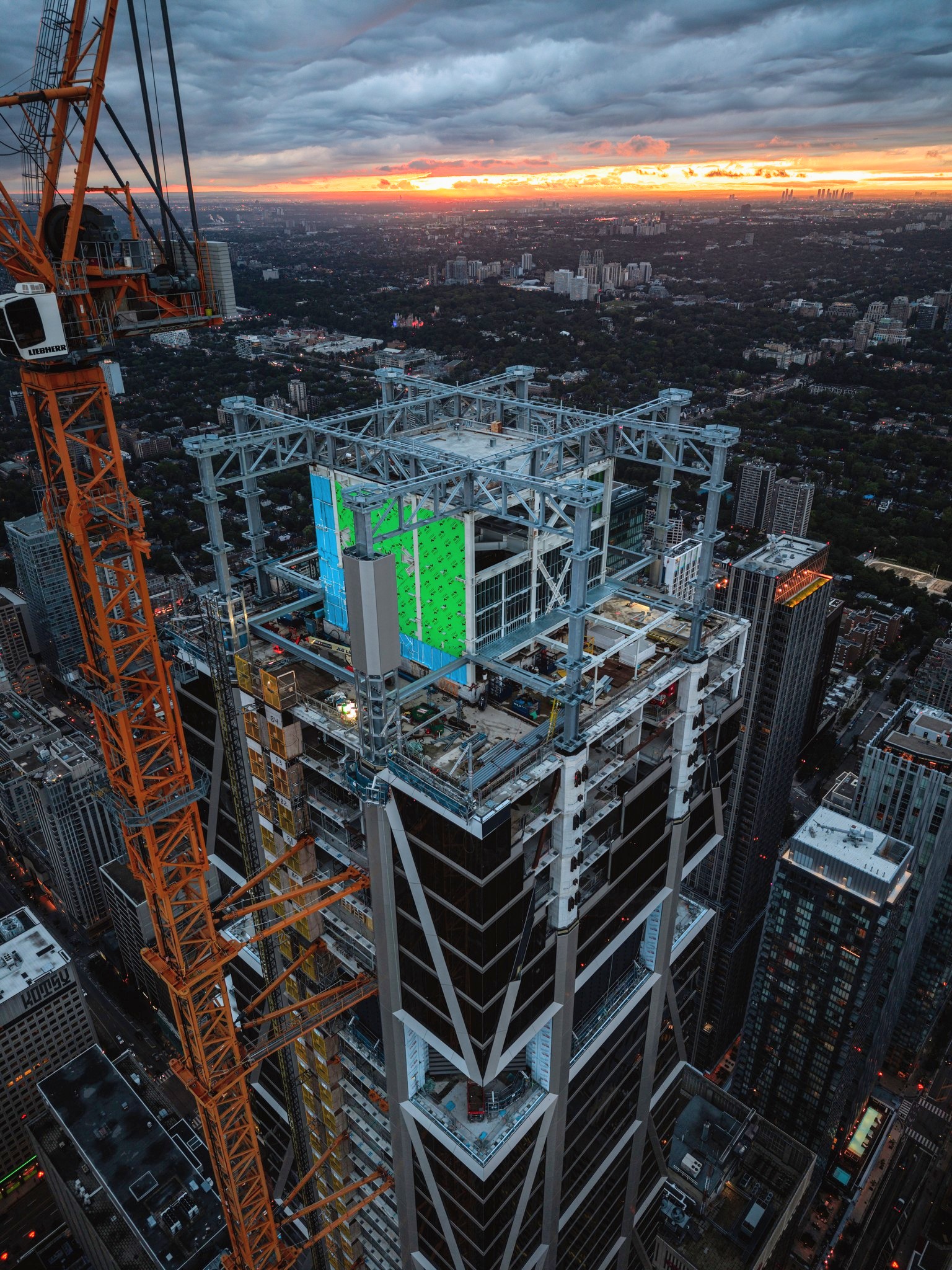 Drone view of One Bloor West's crown showing structural steel framing and the tuned mass damper enclosure