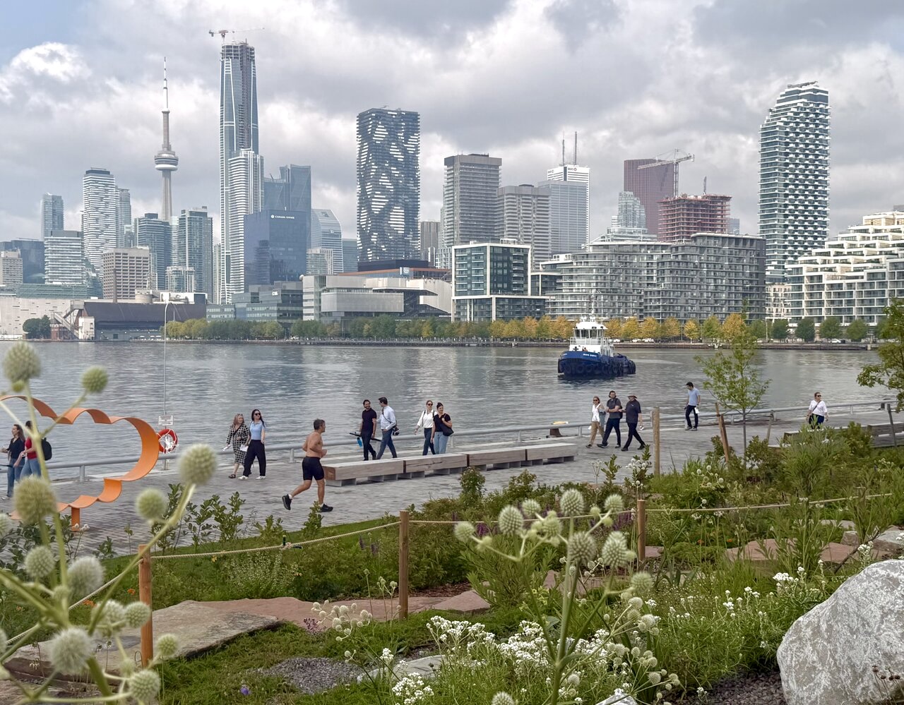 People enjoy the new naturalized water's edge promenade at Biidaasige Park, Toronto