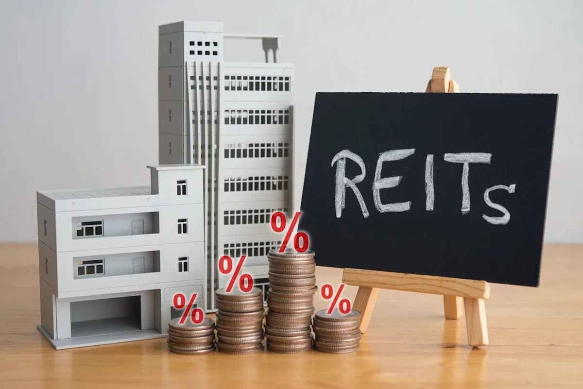 Model buildings alongside stacked coins topped with percentage symbols, representing real estate investment returns