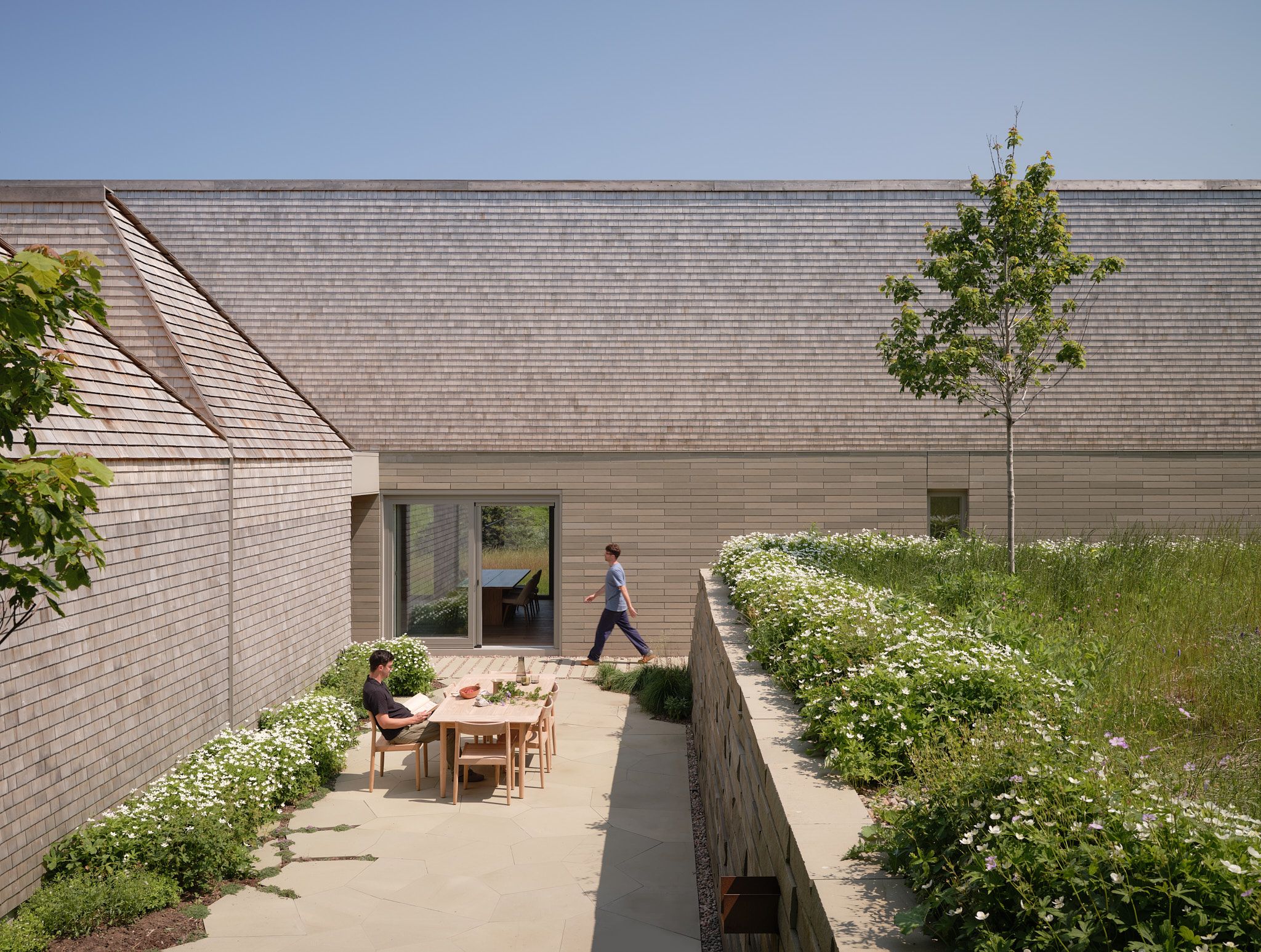 Place of Work's house in a meadow between the forest and the sea, a geometric house set in leafy countryside
