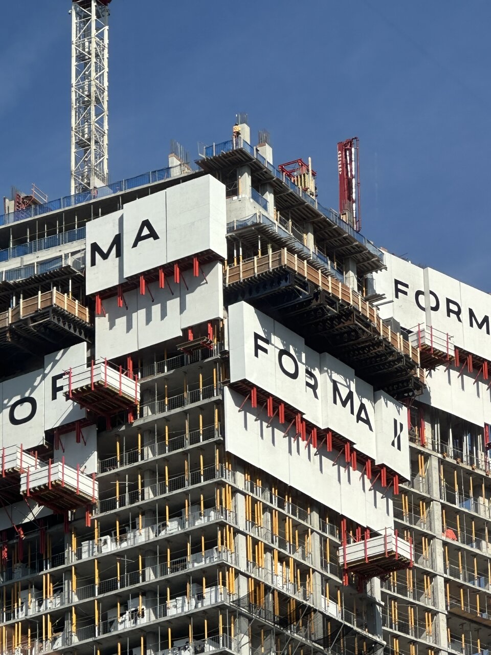 Branded protective walls at the top of Forma break into mismatched sections as the tower shifts floor-plate layouts, Toronto