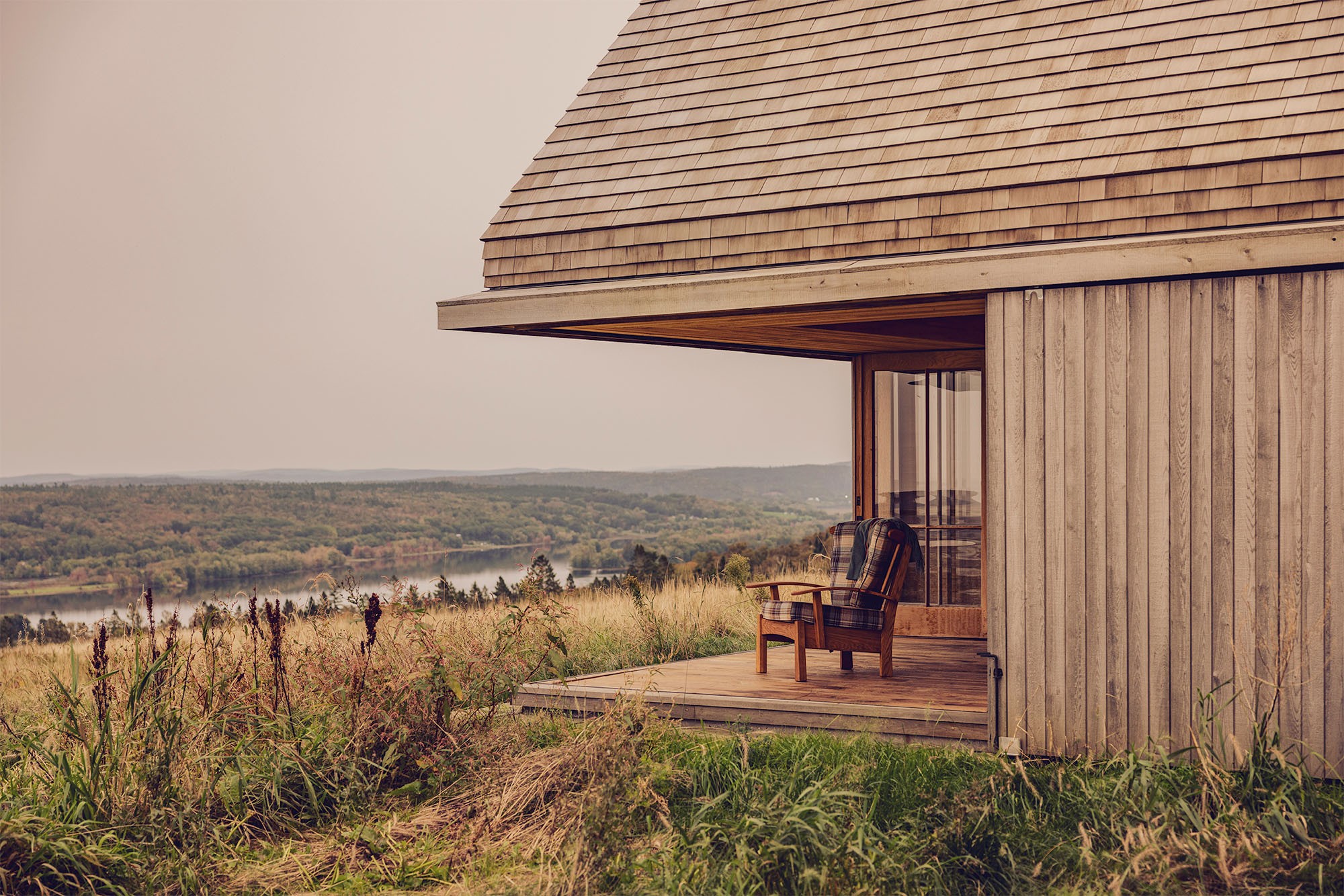 Timber-clad exterior of Hilltop Cottage nestled among trees in New Brunswick
